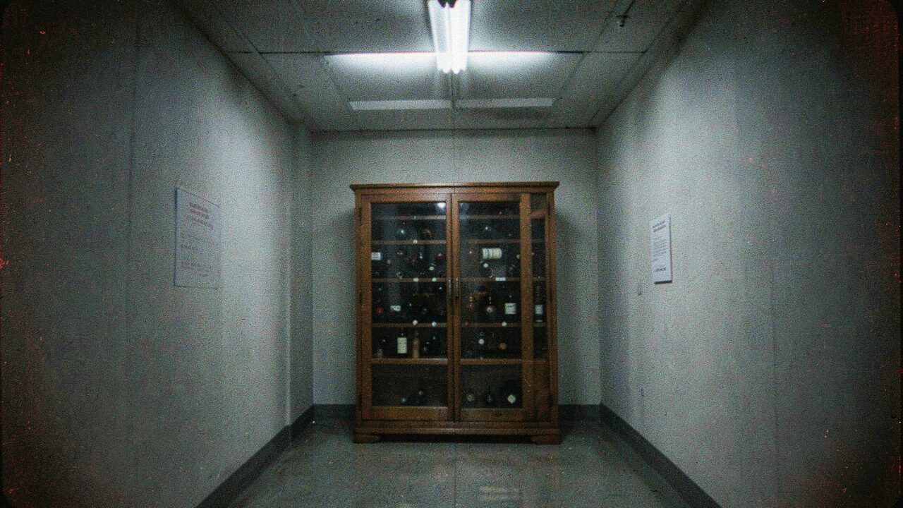 A museum corridor. The box behind glass, dimly lit, performing exactly as advertised.