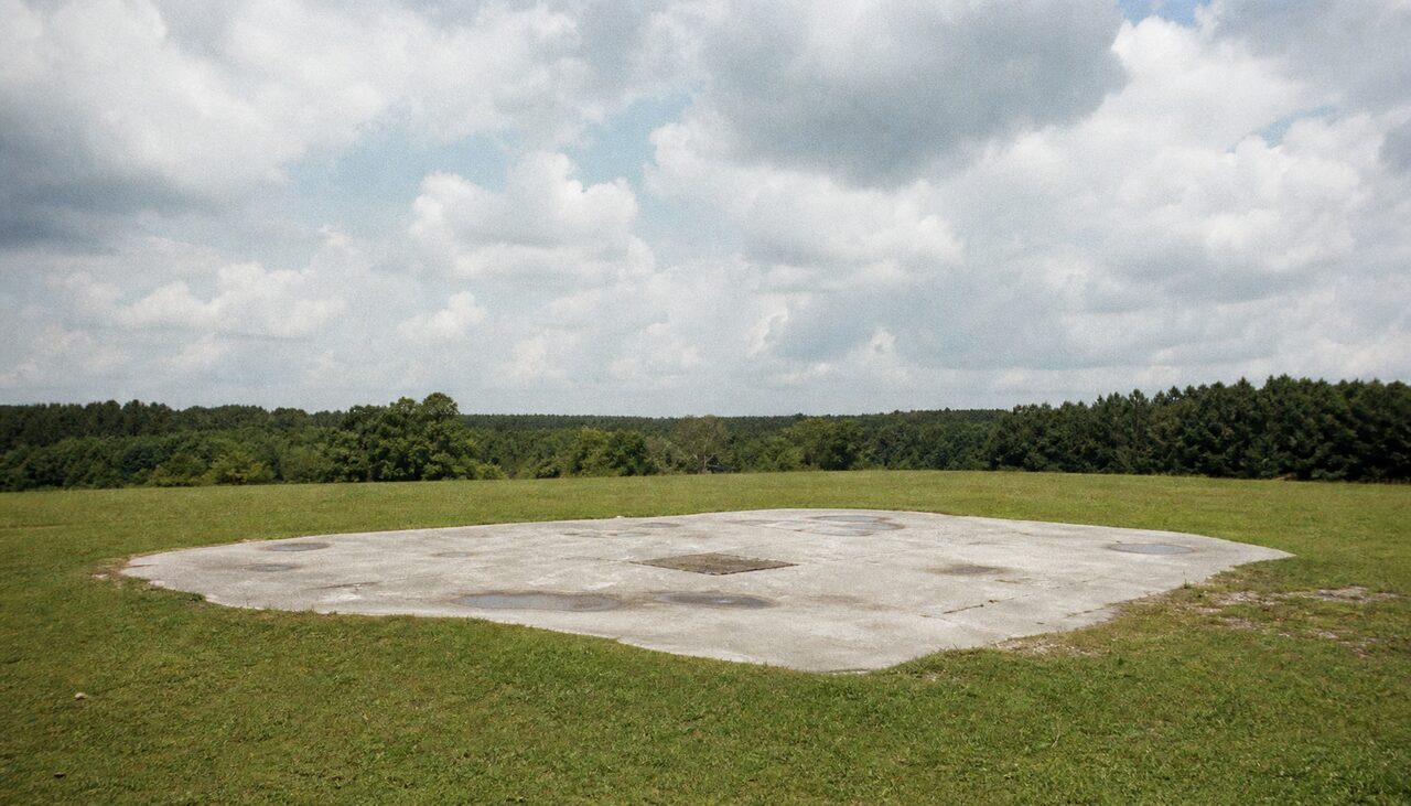 The empty concrete pad where the monument stood. Everyone involved managed to leave without a name attached.