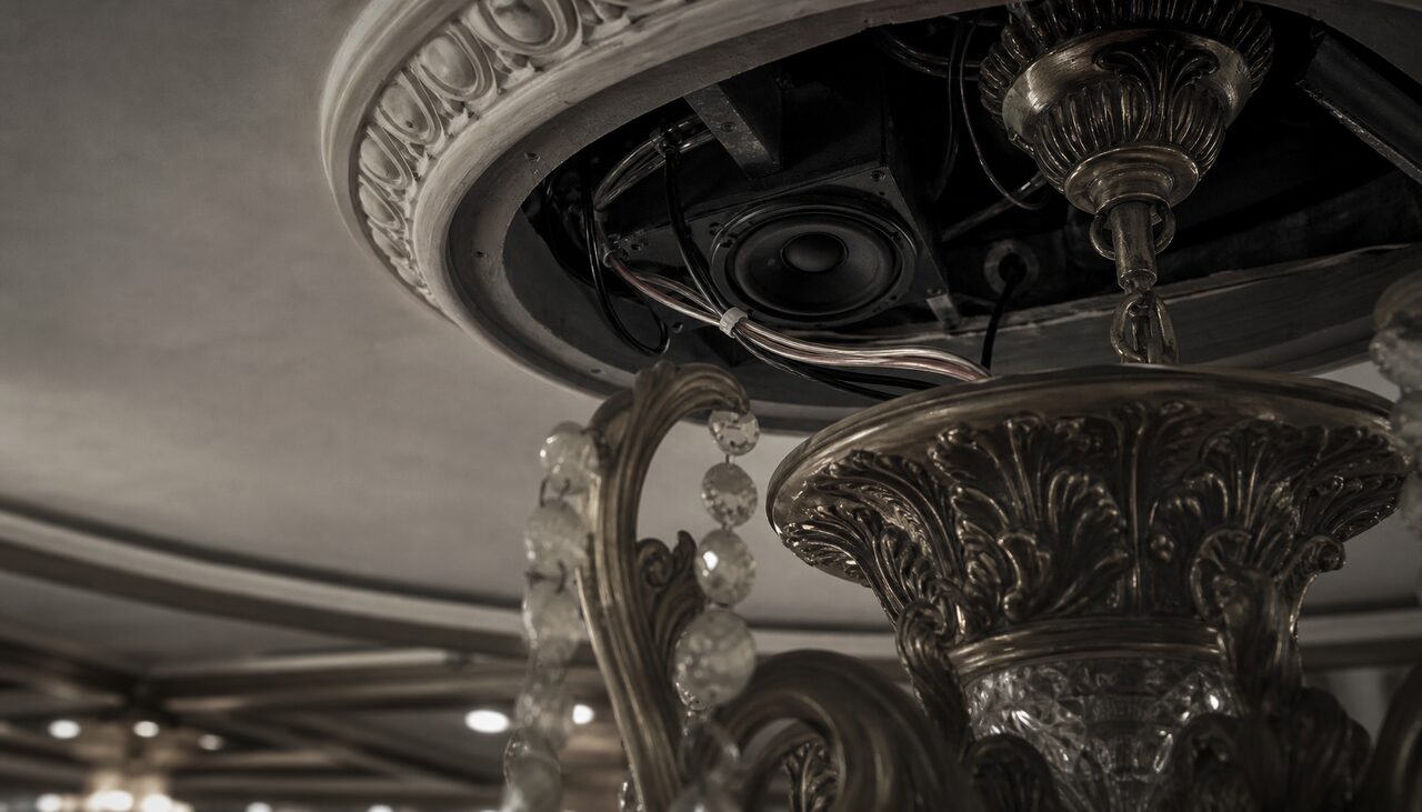 Wiring and a small speaker tucked behind a chandelier. The haunting had a maintenance schedule.