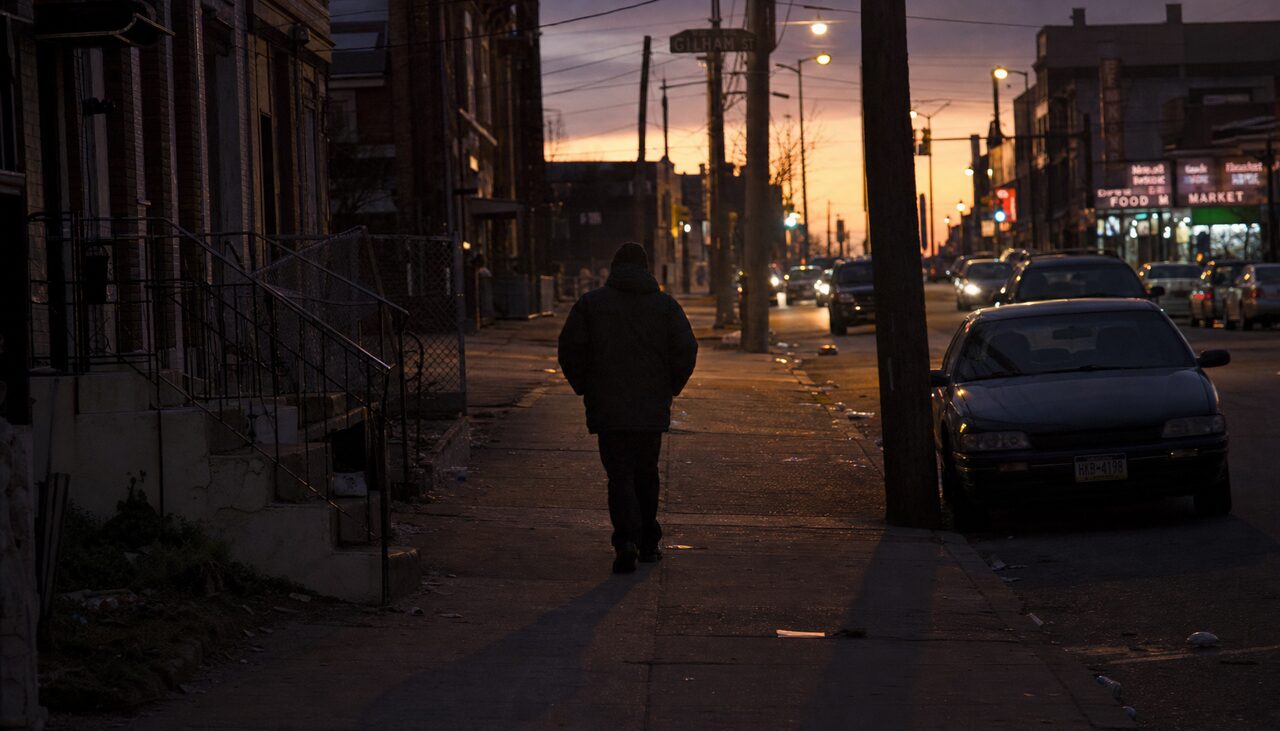 A solitary figure, long shadow, no destination given.